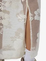 Falda larga color crudo con diseño de encaje floral, corte recto y cintura elástica.