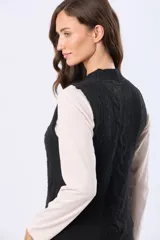 Chaleco tejido color negro, con cuello alto y diseño de trenzas en el frente. Tiene un parche de cuero sintético marrón con logo en el dobladillo inferior.