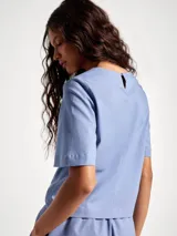 Blusa de manga corta con cuello redondo, confeccionada en tejido de lino con textura natural, de corte recto y ajuste cómodo.