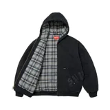 Campera con capucha Supreme de lona color negro, con cierre frontal y bolsillos tipo canguro. Presenta apliques de cuero con tipografía gótica en la parte inferior y forro interior de tela a cuadros.