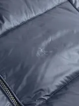 Campera acolchada azul con cuello alto, cierre frontal con cremallera, bolsillos laterales con cremallera, puños y dobladillo con punto canalé y logo de Calvin Klein bordado en el pecho.