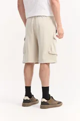 Bermuda cargo de algodón sin frisa color beige, con cintura elastizada, cordón ajustable y amplios bolsillos laterales con solapa.