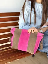 Cartera tipo sobre de cuero con diseño de rayas verticales en tonos verde menta y marrón tostado. Cuenta con detalles de borlas colgantes en los laterales.