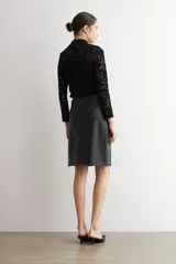 Falda de corte recto y largo midi, confeccionada en eco cuero negro con acabado mate y costuras verticales visibles.