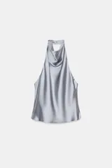 Top blanco satinado con cuello halter y escote fluido. Cierre en la espalda con botones.