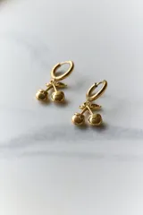 Aros con dije colgante en forma de cerezas, de acero quirúrgico hipoalergénico acabado dorado.