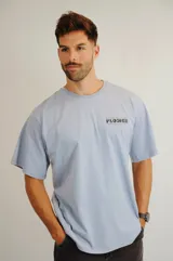 Remera de algodón color celeste, de corte holgado y manga corta. Presenta un estampado gráfico pequeño en el pecho con la frase 'Growing like a flower'.