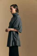 Poncho de tejido de punto color gris, con cuello alto y mangas amplias de diseño holgado.