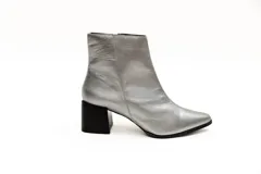 Botas cortas plateadas de cuero con punta fina y cierre lateral. Taco geométrico color negro.