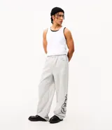 Pantalón de corte super baggy confeccionado en tejido de algodón y poliéster, color gris melange. Presenta un diseño urbano con estampado de serpiente tribal en color negro en las piernas, cintura elástica y bolsillos laterales.
