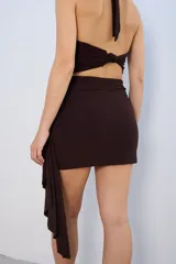 Minifalda negra con drapeado lateral y aplique metálico dorado.