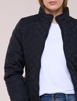 Campera capitoneada negra con costuras multidireccionales, cuello alto, cierre frontal y bolsillos laterales con cierre.