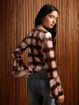 Blusa de terciopelo con estampado a cuadros, corte asimétrico y mangas largas acampanadas.