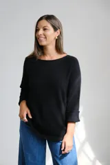 Sweter de punto color negro, con escote a la base y mangas largas con puños doblados. Presenta un corte holgado y diseño minimalista.