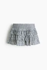 Short pollera mini de viscosa con volados, sección fruncida en la cintura y estampado de patrón ornamental en tonos azules y blancos.