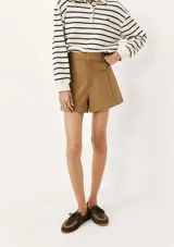 Short de sastre color beige, de tiro alto, con bolsillos laterales tipo ojal y costuras verticales decorativas en el frente.