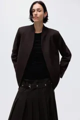 Blazer color marrón oscuro con cuello elevado, hombreras, abertura en los puños y bolsillos delanteros ribeteados. Incluye un cinturón fino con hebilla metálica para ajustar la cintura.
