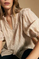 Camisa blanca de manga corta abullonada con terminación elastizada y cuello con leve frunce. Presenta una estampa floral integral.