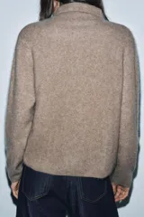Chaqueta de punto confeccionada en lana, con cuello subido, manga larga y cierre frontal con botones. Presenta un acabado con efecto cepillado.
