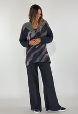 Saco de lana color verde militar con estampado abstracto en tonos verde oliva y detalles bordados en rojo. Tiene cuello solapa, cierre frontal con botones de madera y puños acanalados.