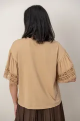 Remera de algodón color blanco, con cuello redondo y mangas cortas holgadas que presentan detalles de encaje broderie.