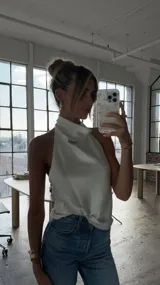 Top de satén color blanco con cuello halter y espalda descubierta. Presenta una caída fluida y un diseño minimalista sin mangas.