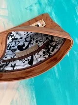 Sobre clutch confeccionado en suave cuero terra con arte exclusivo de Carolina De Cunto, cuenta con cierre superior y correa de muñeca extraíble.