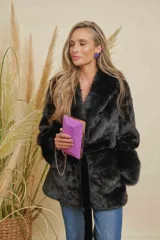 Abrigo negro de piel sintética con cuello solapa, manga larga y cinturón de tela para ajustar en la cintura.