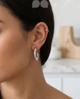 Aros tipo argolla de acero plateado con textura rayada en la superficie. Diseño moderno y minimalista.