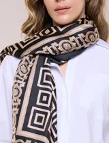 Pashmina de satén con estampado geométrico en tonos negros, beige y dorados, de forma rectangular y gran tamaño.