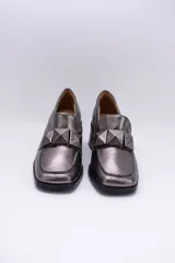 Mocasines plateados de cuero con aplique geométrico al tono y taco cuadrado.