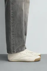 Zapatilla de cordones estilo retro, color negro con detalles en blanco y suela de goma color caramelo.