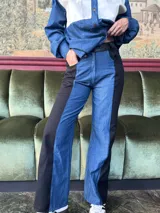 Pantalón de tiro alto con pierna ancha, confeccionado en denim azul y cuerina negra.