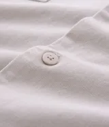 Camisa boxy color crema de algodón texturizado, con cuello inglés, mangas cortas, bolsillos delanteros y lettering bordado.