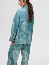 Pantalón de tiro alto con corte recto y holgado, confeccionado en tela liviana con estampado tipo tie-dye en tonos azul y blanco.