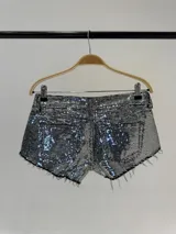 Short de tiro bajo confeccionado en tela cubierta de lentejuelas plateadas, con diseño de cinco bolsillos y ruedo deshilachado.