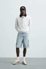 Bermuda de denim de algodón, color celeste lavado, de corte relajado (relaxed fit). Presenta cinco bolsillos, incluyendo bolsillos cargo plastrón con solapa en las perneras.