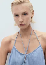 Vestido midi de corte recto y diseño holgado, confeccionado en tejido mezcla de algodón y lino con efecto denim. Presenta cuello de pico con detalle de lazo frontal y tirantes finos ajustables.