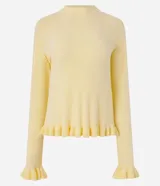 Suéter de tricot color amarillo claro, de manga larga y cuello redondo. Presenta detalles de volados acanalados en el ruedo y en los puños.