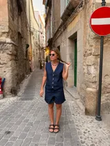 Short de jean azul oscuro con costuras contrastantes en tono tostado, de tiro medio y corte clásico.