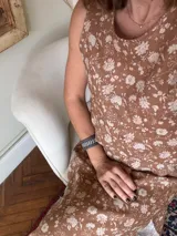 Vestido midi sin mangas, con cuello redondo y tajos laterales en el ruedo. Presenta un cierre con botón en la espalda y un diseño estampado floral sobre base de lino.