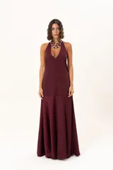 Vestido largo de color bordó con escote en V profundo y diseño de espalda descubierta. Presenta un corte fluido con falda amplia y caída suave.