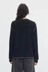 Remera de manga larga negra con bolsillo frontal en el pecho y costuras a la vista en contraste de color gris.