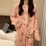 Conjunto de pijama de dos piezas confeccionado en plush suave, compuesto por una remera de manga larga y pantalón largo. Presenta un diseño estampado de duraznos sobre fondo color crema.