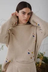 Sweater beige de tejido de punto acanalado con cuello redondo y mangas largas. Presenta apliques de manchas de colores en el frente y las mangas.