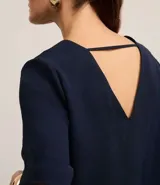 Blusa Cortelle de corte holgado confeccionada en crepé, con escote en V delantero y trasero, y mangas cortas. Presenta una tira decorativa entre los hombros en la espalda.