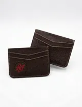 Tarjetero de cuero marrón con textura granulada, diseño minimalista con ranuras para tarjetas y detalle de logo bordado en hilo rojo.