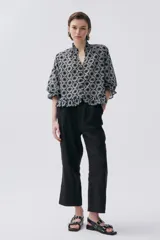 Blusa negra con estampado de flores blancas, escote en V con volados, mangas 3/4 abullonadas con elástico y botones forrados.