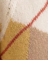 Cárdigan tejido de punto con diseño de rombos, en colores crema, violeta y detalles en rojo. Presenta cuello redondo, cierre frontal con botones de madera y textura acanalada en los bordes.