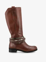 Bota de caña alta confeccionada en cuero italiano color marrón, con punta redondeada y taco bajo. Destaca por sus correas decorativas en el tobillo con tachas metálicas circulares y hebilla de ajuste.